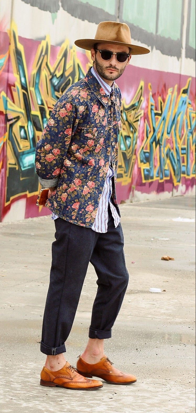 Christopher Jay Heller wearing a tan fur felt wide brim hat with sunglasses, floral jacket and loafers modeling in front of a downtown los angeles mural.