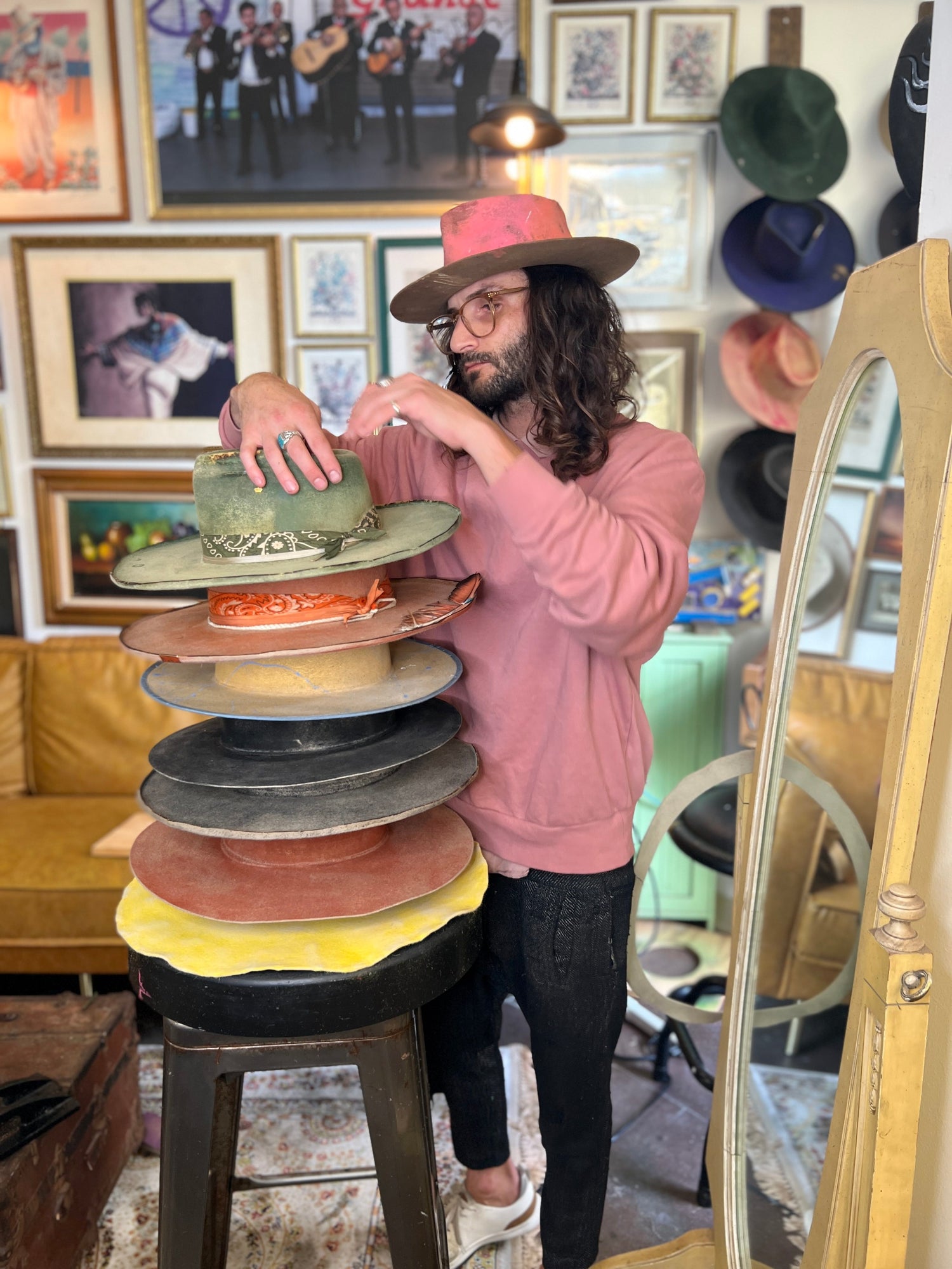 Person arranging hats on a stool in a room with hat display and decor.