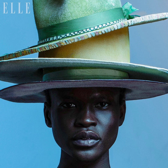 Person wearing a multiple hats with a blue background, featuring the Elle logo.