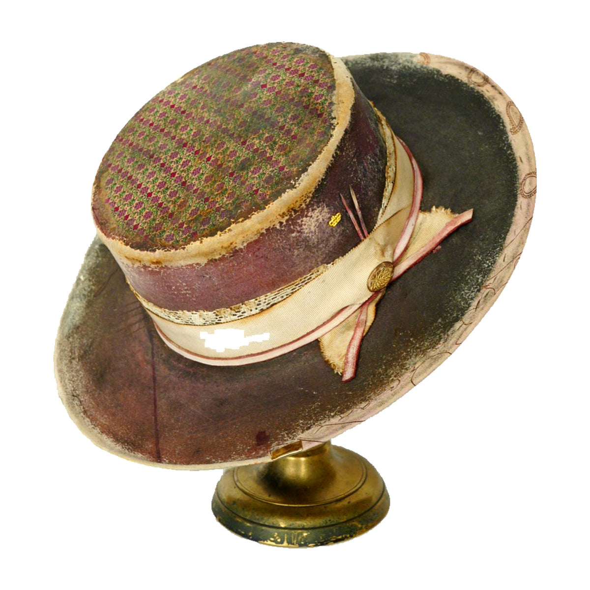A vintage-style wide-brim hat displayed on a small gold stand against a plain white background. The hat features a dark brown brim, a gold-and-purple patterned crown, and a cream ribbon with a gold button and bow.
