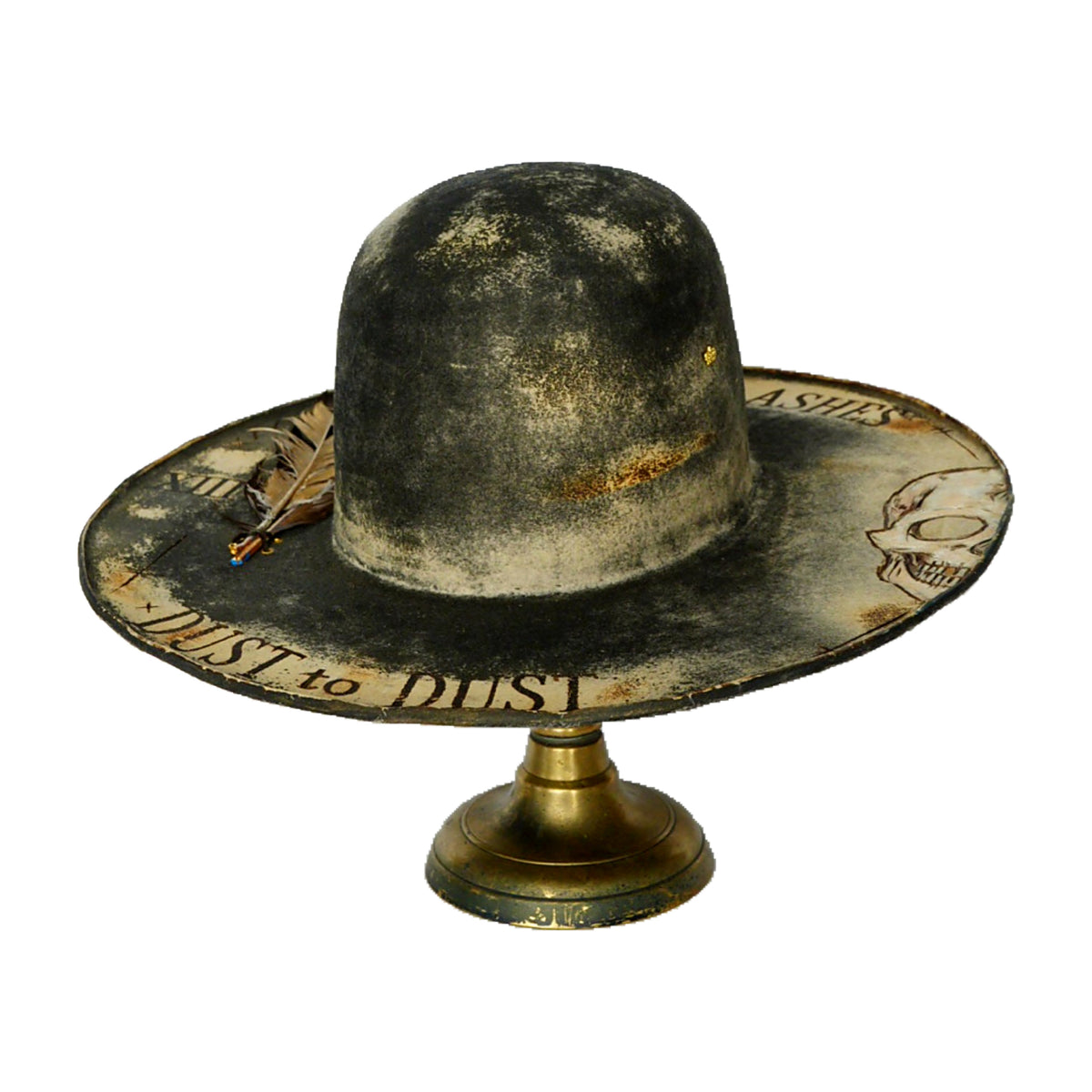 A distressed, vintage-style black and beige sombrero hat displayed on a gold-colored metal stand against a plain white background.