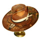 A distressed brown cowboy hat with a cream ribbon band and western-style painted details, displayed on a gold-colored stand against a white background.