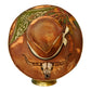 A brown cowboy hat with hand-painted rustic western designs, including a skull motif on the brim and a green paisley pattern on the crown, displayed on a small gold-colored stand against a white background.