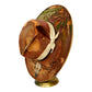 A decorative brown wide-brim hat displayed on a small gold stand against a plain white background. The hat has a distressed finish with gold-toned wear, a cream ribbon tied around the crown, a feather accent, and western-style painted details including a skull motif near the brim.